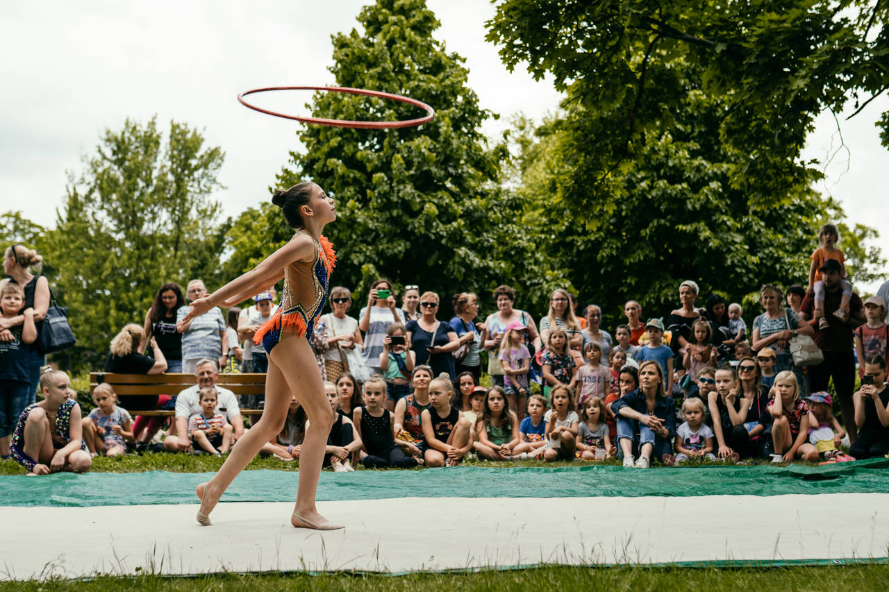 Akrobatka podrzuca do góry koło hula-hop, w tle publiczność, która się jej przygląda